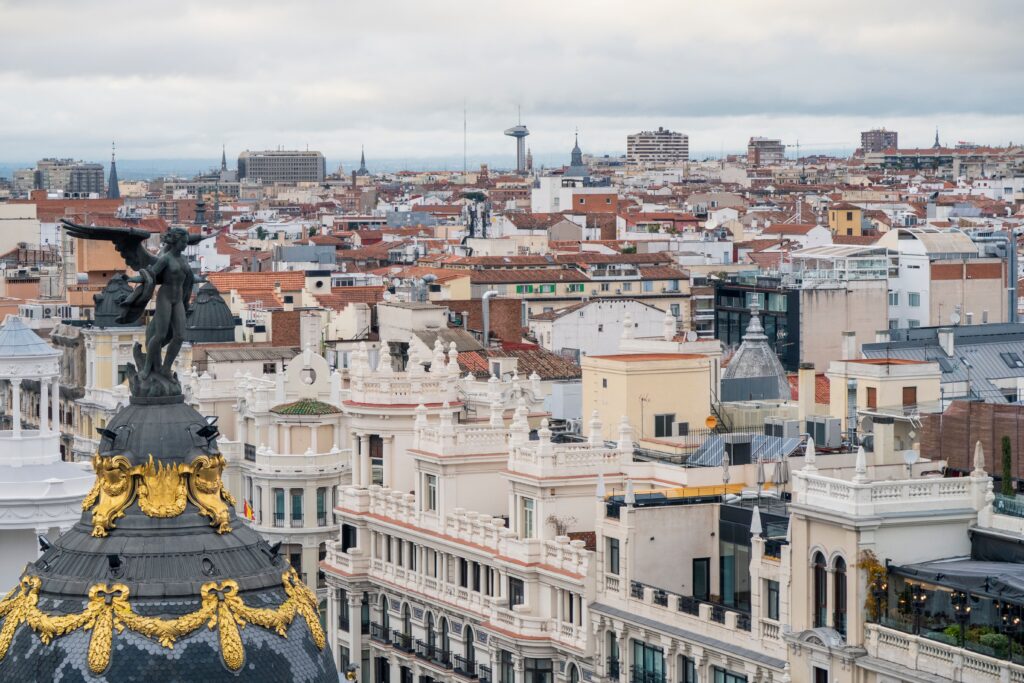 A captivating view of Madrid's iconic Metropolis Building amidst historic rooftops.
